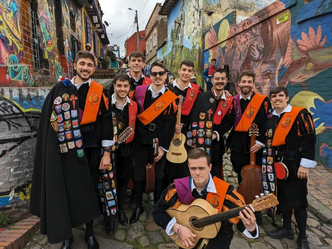 La tuna posando con sus capas entre los murales de una calle de Valencia